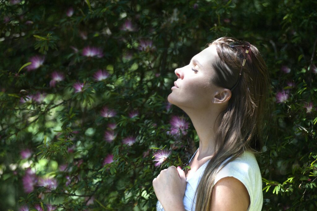 pexels photo 321576 321576 A woman enjoying a serene moment in a sunlit garden, surrounded by vibrant flowers.